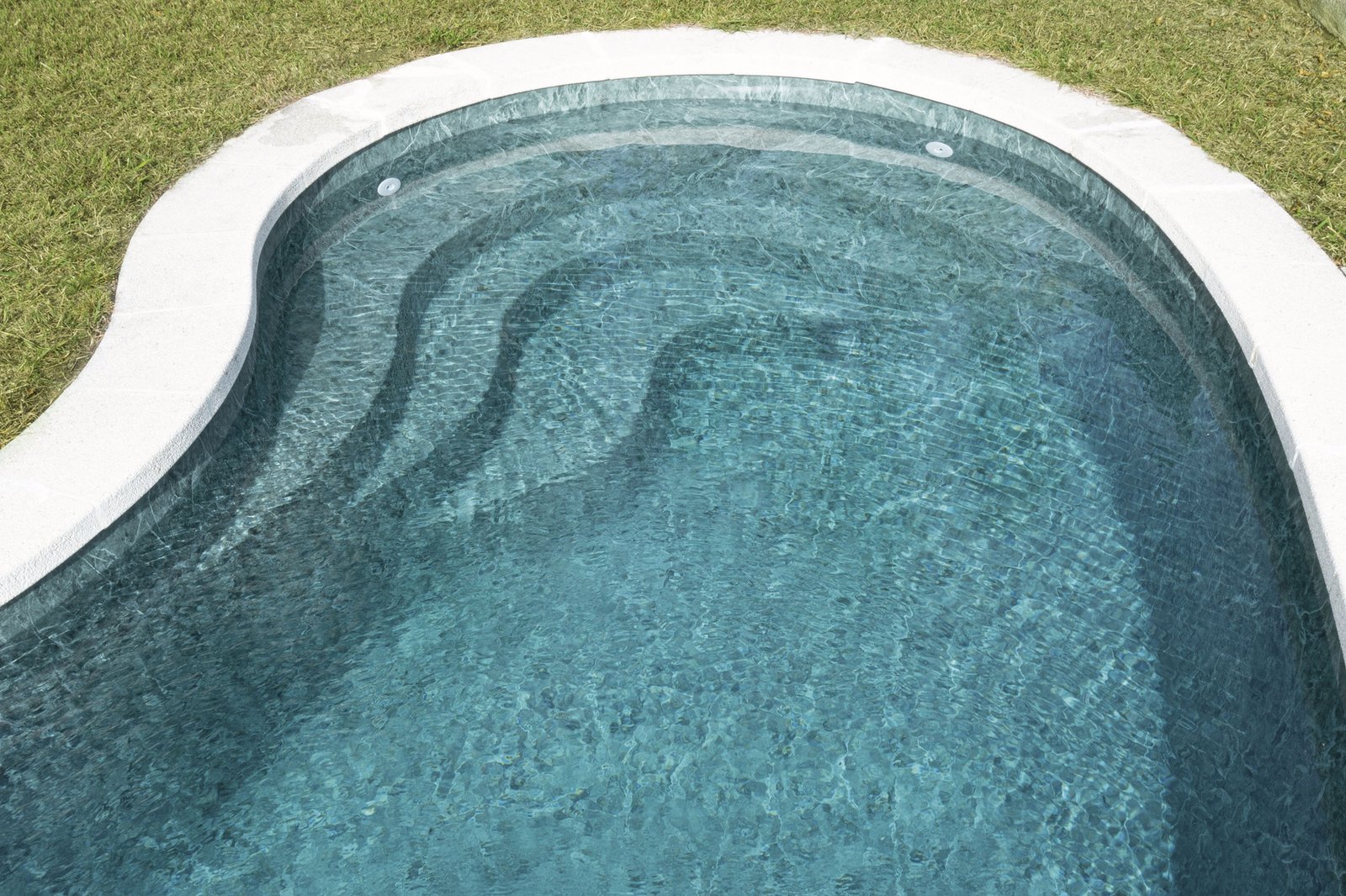 Piscina de formas curvas con revestimiento claro